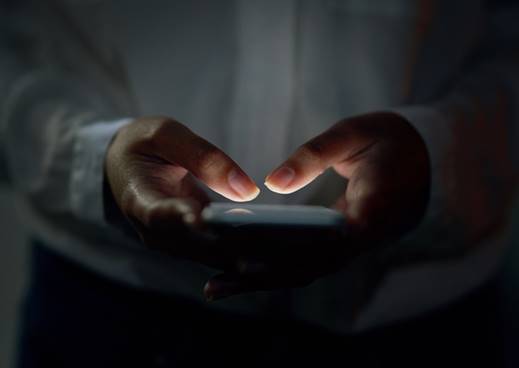 Close-up of hands holding a glowing smartphone in the dark. The image is used in an article draft in the context of website content editing.
